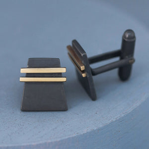 Pair of Black and Gold cufflinks on deep blue background styled for photography, ideal premium special cufflinks for groom or best man gifts.