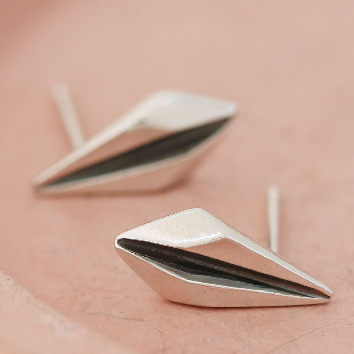 Silver art deco earrings on pink dish showing minimalist geometric shape.