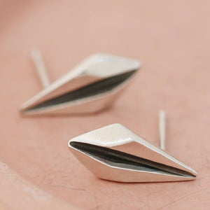 Silver art deco earrings on pink dish showing minimalist geometric shape.