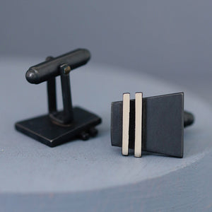 Close-up of handmade black cufflinks on a deep blue background, showing oxidised matte finish and polished silver edges. Ideal birthday gift ideas for husband.