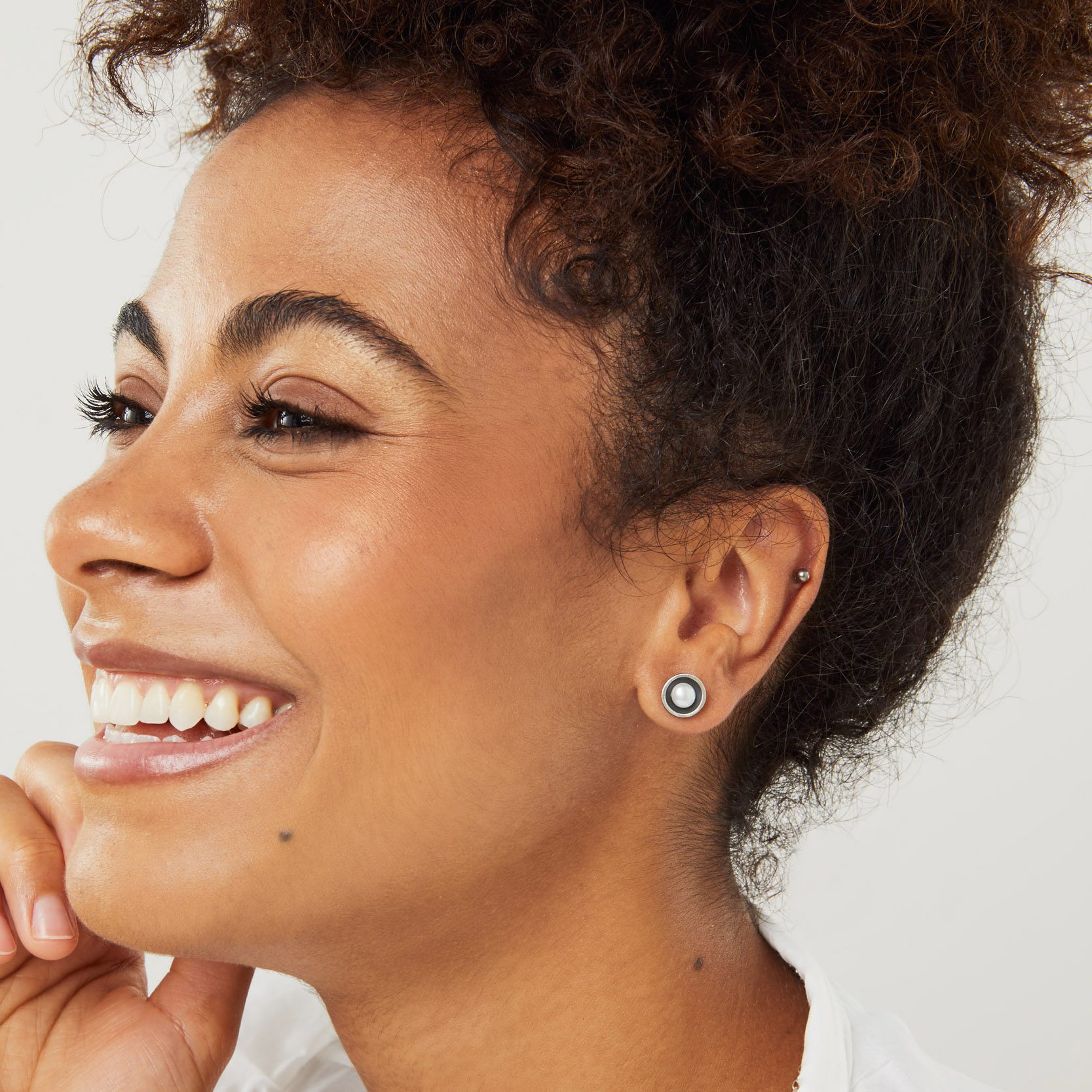 Side profile of model wearing modern black pearl stud earrings with hair up highlighting the dome shape and pearl contrast