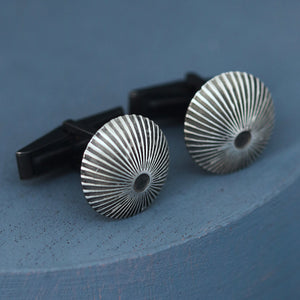 Angled view of silver and black cufflinks on deep blue background, stylish gift for man who loves unique mens luxury cufflinks.