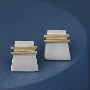 Silver and gold cufflinks photographed on a deep blue background to showcase geometric detailing; elegant luxury cufflinks gift for him for weddings or special occasions.