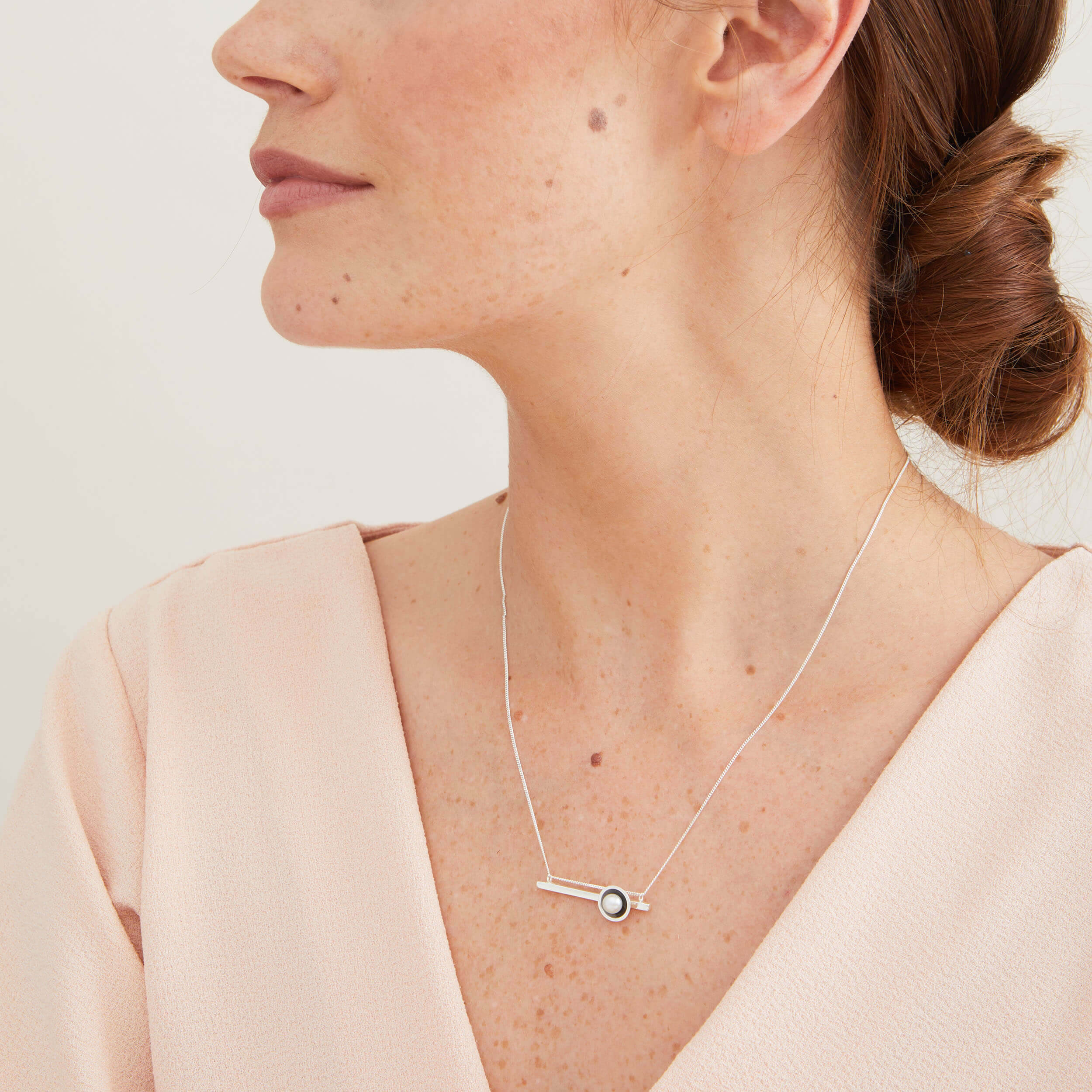 Layering pearl necklace worn on the neckline, showcasing the contemporary geometric design and freshwater pearl.