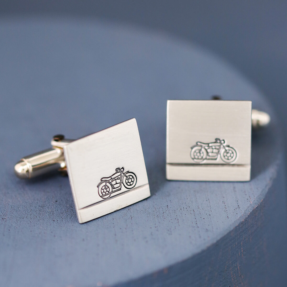 Handcrafted motorbike cufflinks on deep blue surface, a unique wedding day gift for a motorbike mad groom