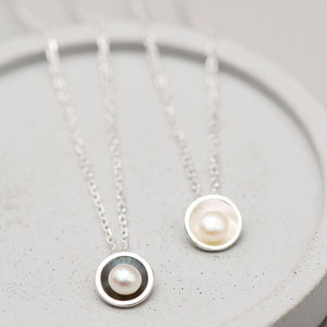 Black pearl pendant necklace beside the polished sterling silver version, highlighting the contrast between the two handcrafted finishes.