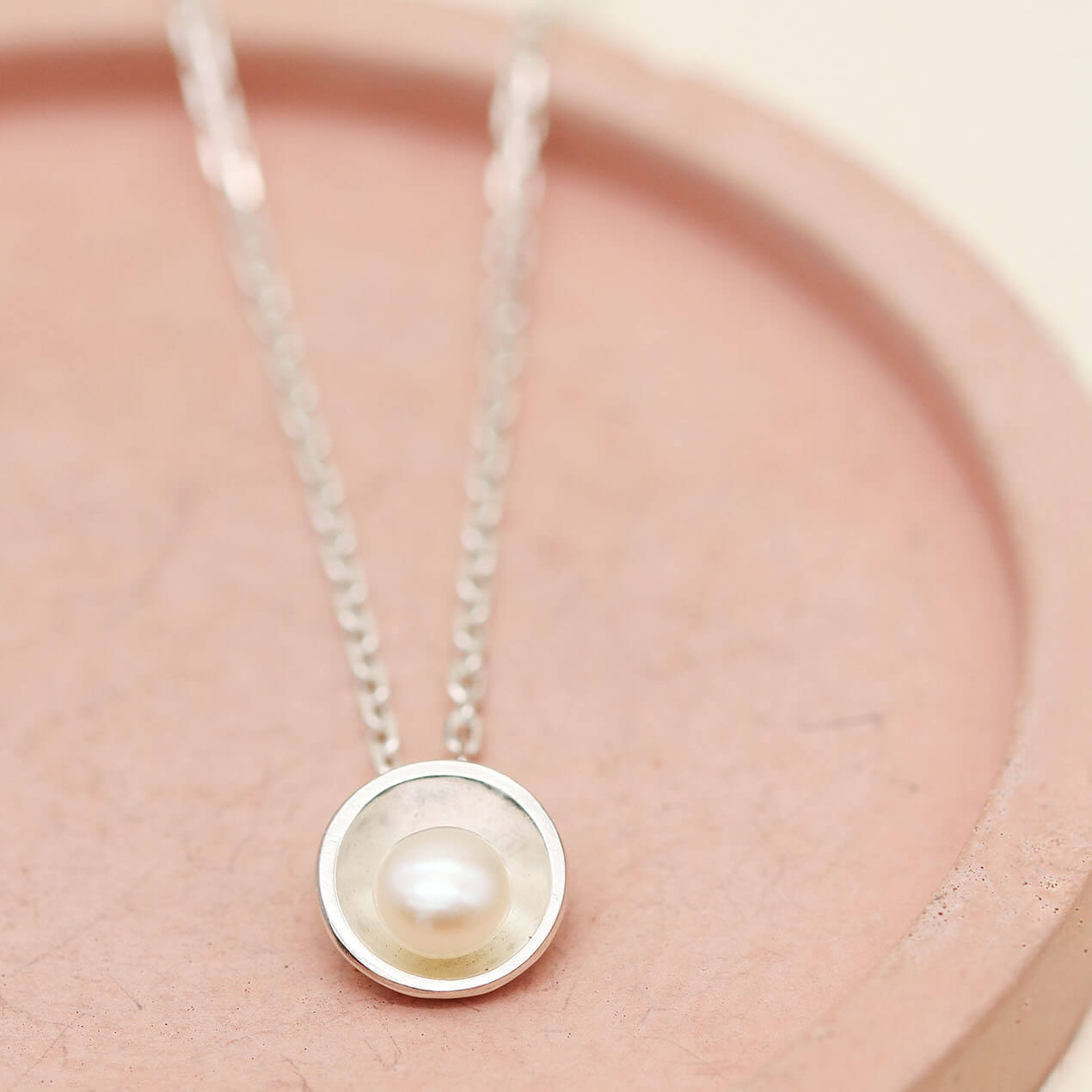 Close-up of a silver pearl pendant necklace featuring a genuine freshwater pearl in a polished sterling silver setting.