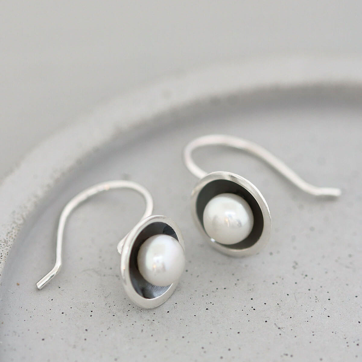 Detail of handmade oxidised sterling silver pearl earrings highlighting the contrast between the blackened silver and lustrous freshwater pearls.