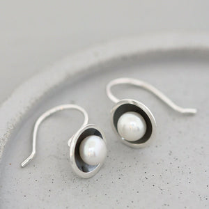 Detail of handmade oxidised sterling silver pearl earrings highlighting the contrast between the blackened silver and lustrous freshwater pearls.
