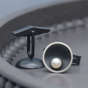 Handmade black pearl cufflinks for men in oxidised sterling silver with genuine freshwater pearls, photographed on a dark grey dish.