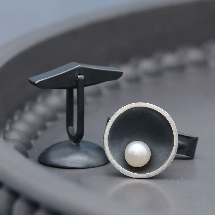Handmade black pearl cufflinks for men in oxidised sterling silver with genuine freshwater pearls, photographed on a dark grey dish.