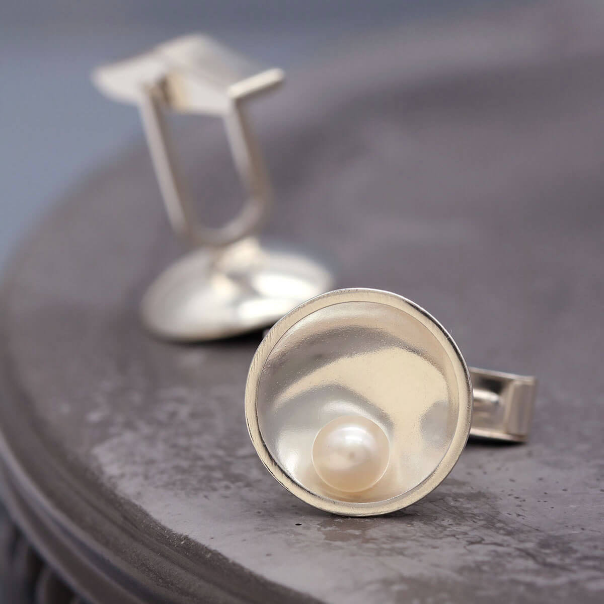 Close up of sterling silver pearl cufflinks showing handcrafted details and geometric styling.