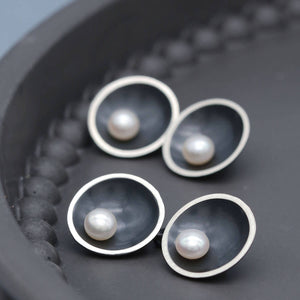 Handmade black double-sided pearl cufflinks in oxidised sterling silver with genuine freshwater pearls on a dark grey dish.