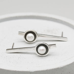 Long drop pearl earrings handcrafted from oxidised sterling silver with luminous freshwater pearls on a grey dish.
