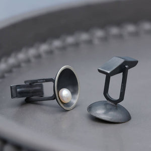 Close up of Art Deco pearl cufflinks showcasing traditional silversmithing craftsmanship and geometric design.
