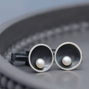 Men's black pearl cufflinks in sterling silver displayed on a dark grey background.