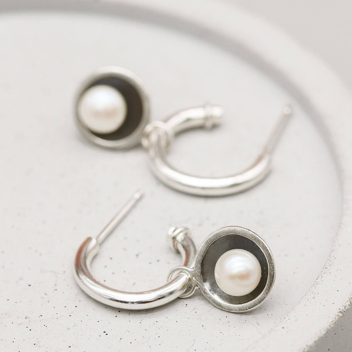 Contemporary hoop earrings with pearl drop crafted from sterling silver with oxidised pearl charm settings.
