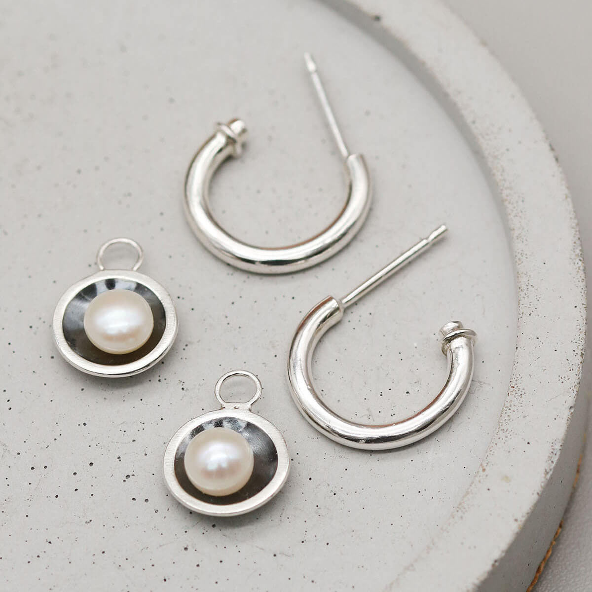 Black pearl hoop earrings featuring removable pearl charms and solid sterling silver hoops.