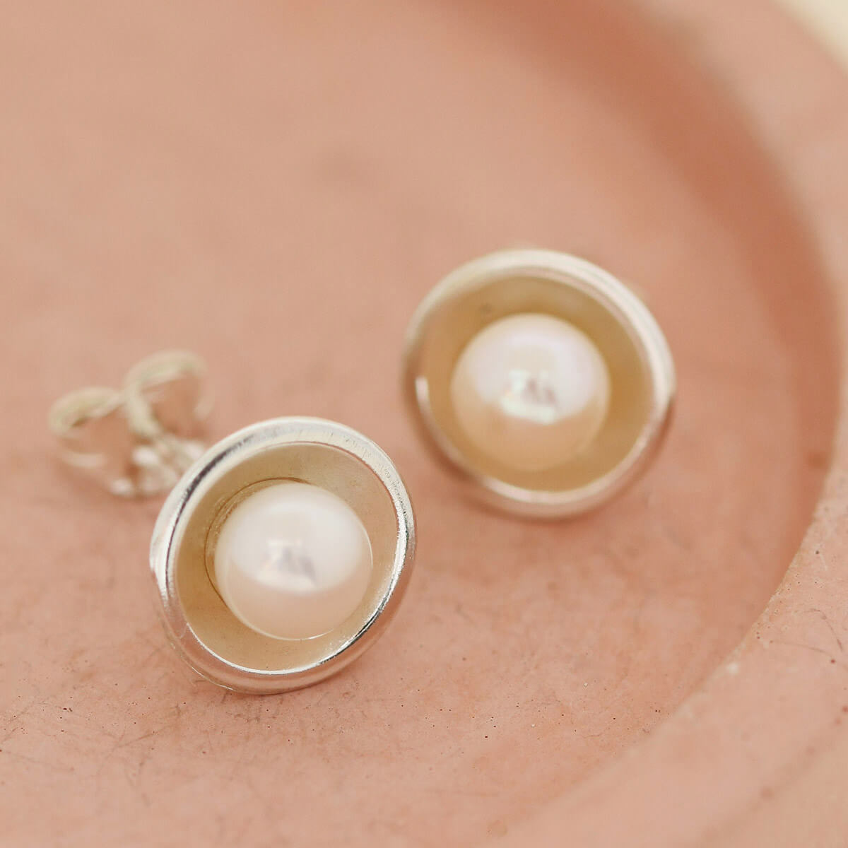 Real pearl stud earrings on a pink dish — classic Pearl Earrings for women and elegant real pearl stud earrings handmade in silver.