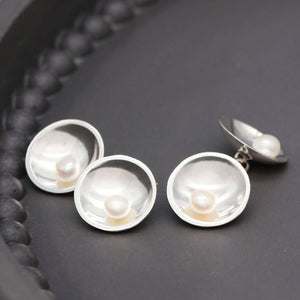 Close up of men's pearl cufflinks showing traditional silversmithing craftsmanship and chain-linked construction.