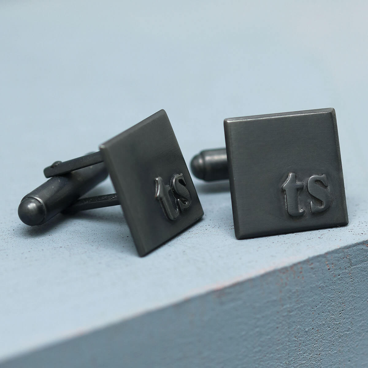 TS initial cufflinks in matte black sterling silver, personalised gift for a son, groom or husband on a deep blue background