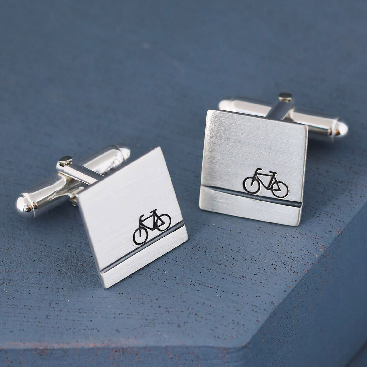 Personalised bike cufflinks on deep blue background showing elegant cufflink fittings, perfect cycling gifts for him or thoughtful wedding accessories.