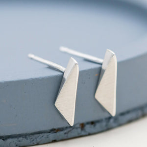 Kite-shaped sterling silver stud earrings, small everyday earrings and thoughtful jewellery gift for her, on a deep blue dish