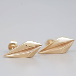 Detailed texture of gold geometric earrings on pale grey, classic art deco design for her.