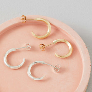 9ct hoop earrings shown beside silver hoops on pale pink dish, real gold small hoop earrings comparison