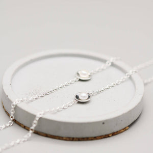 Handmade sterling silver pearl bracelets in polished and oxidised finishes displayed side by side on a grey dish.