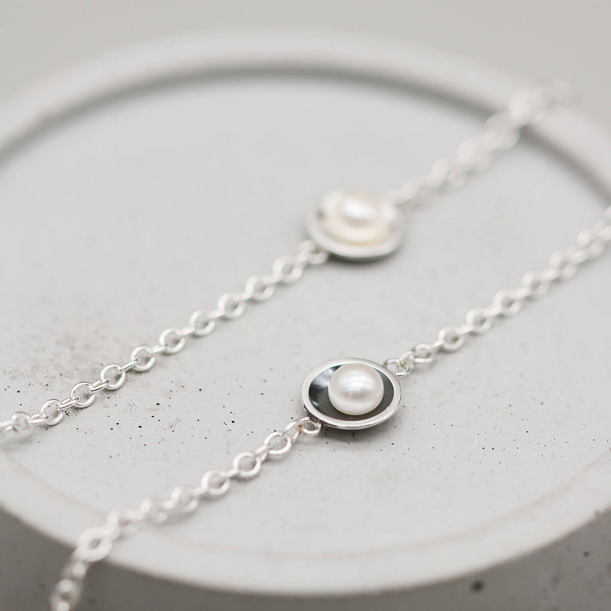 Matching black and silver pearl bracelets featuring genuine freshwater pearls and handcrafted sterling silver settings.