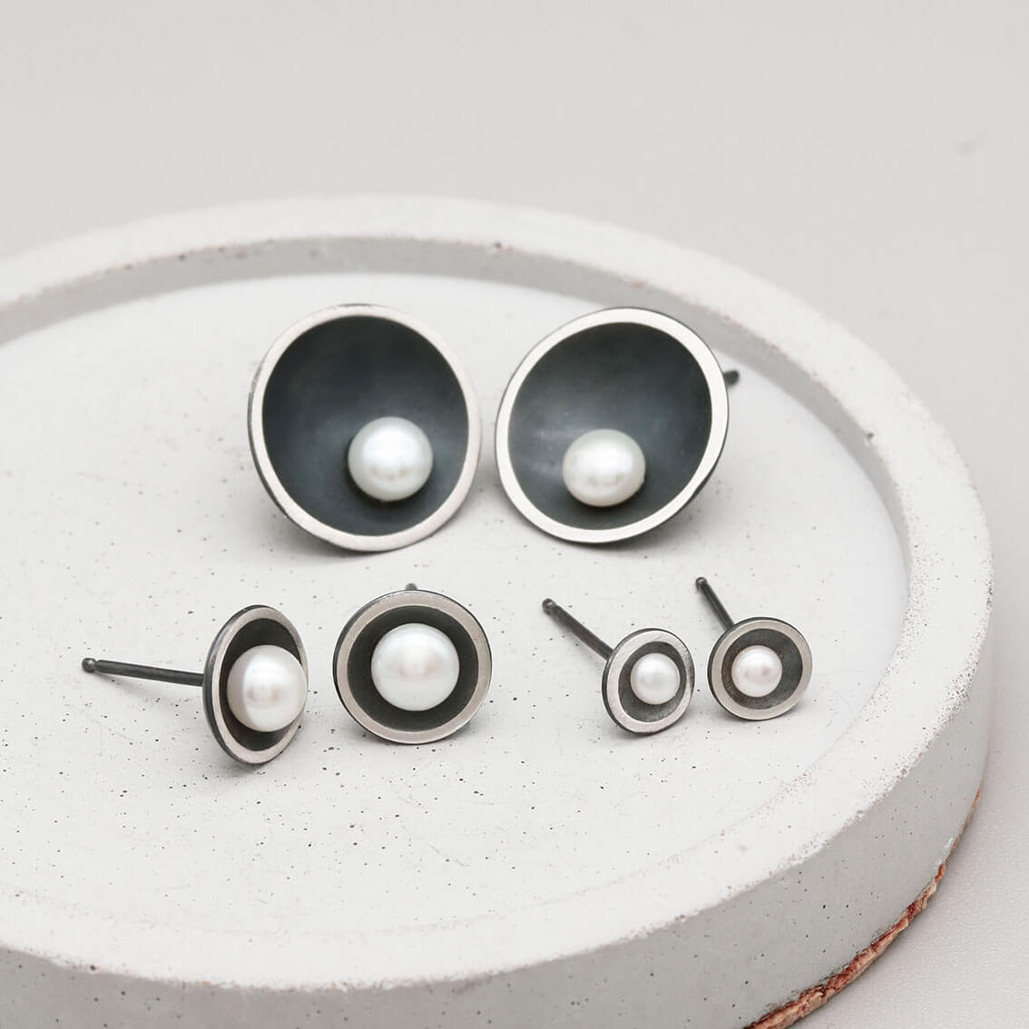 Size comparison of Petite, Classic and Signature black pearl stud earrings in handcrafted oxidised sterling silver.