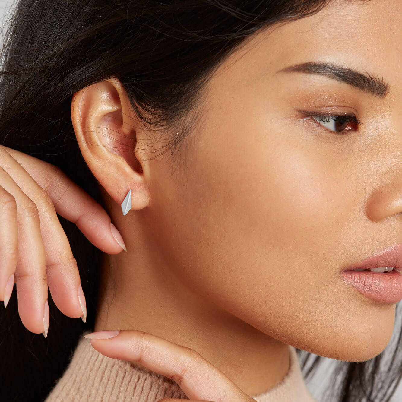 Model wearing sterling silver stud earrings as an everyday jewellery look, small silver kite studs with a simple geometric shape