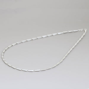 Silver link necklace displayed in full length on a grey surface, showing the continuous Art Deco pattern — a striking contemporary necklace gift idea for women.