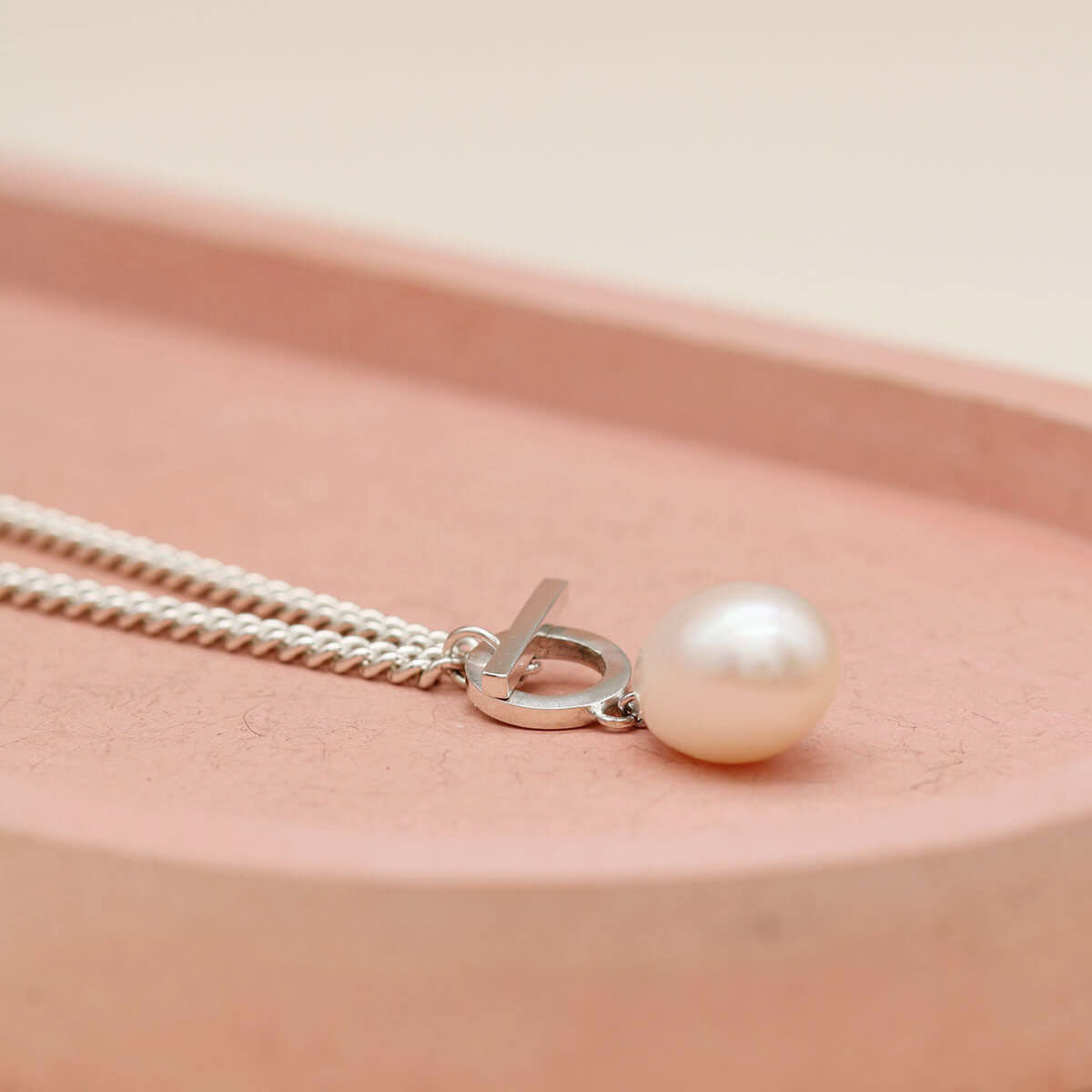 Sterling silver toggle pearl necklace showcasing a bold curb chain and elegant front T-bar fastening.