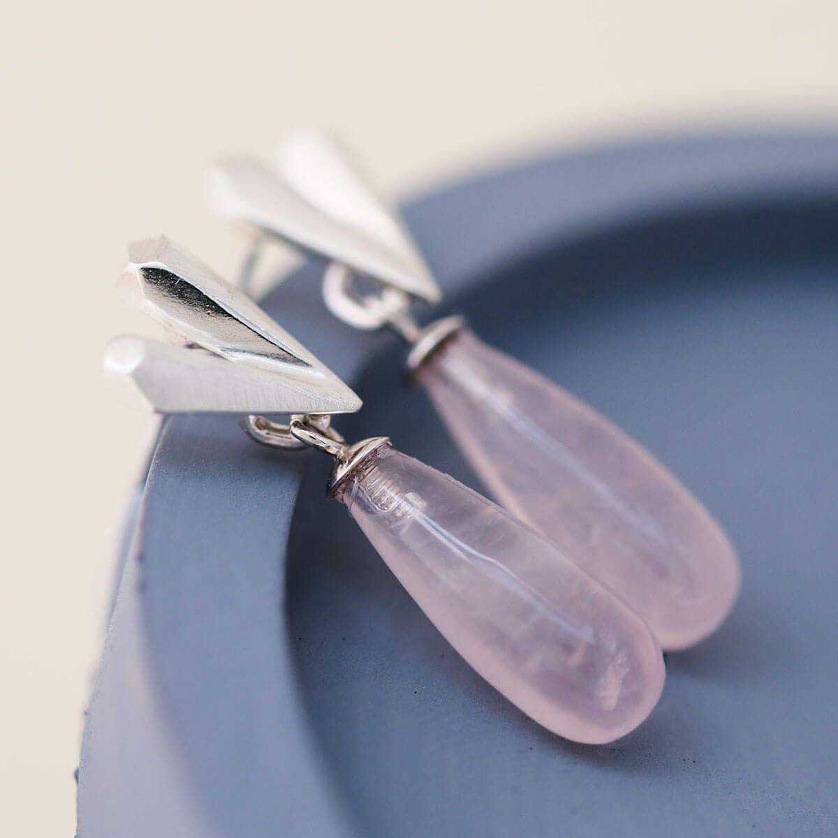 Pink heart earrings showing faceted silver heart detail and rose quartz drop, heart dangle earrings displayed on a blue dish