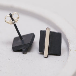 Close-up of silver and black earrings on a grey dish showing the polished silver line, great anniversary gift idea.