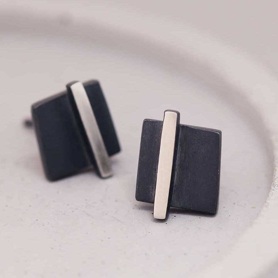 Silver and black earrings on a grey dish showcasing the bold contrast centre, unique graduation gift for her.