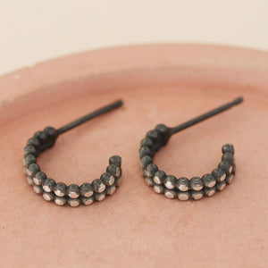 Silver and black hoop earrings flat lay on a pink dish, minimalist huggie earrings