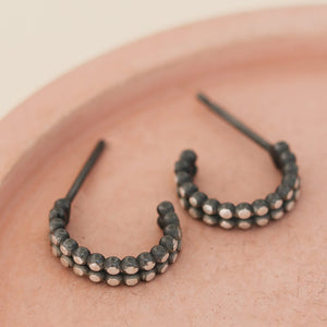Detail view of silver and black hoop earrings on a pink dish, little black hoop earrings handmade