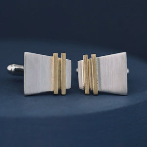 Close-up of silver and gold cufflinks on a deep blue background highlighting the Art Deco inspired gold stripe; perfect luxury cufflinks for graduation gifting.