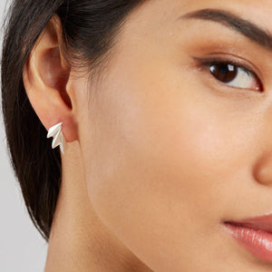 Model wearing art deco silver earrings vertically to show the elegant curved silhouette.