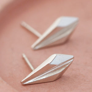 Art deco stud earrings photographed on a textured pink dish, emphasising their minimalist geometric shape for stylish everyday wear or anniversary gifting.