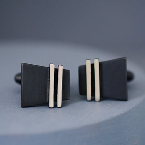 Pair of black cufflinks side by side on deep blue background, perfect birthday gift idea for husband or timeless keepsake for the groom.