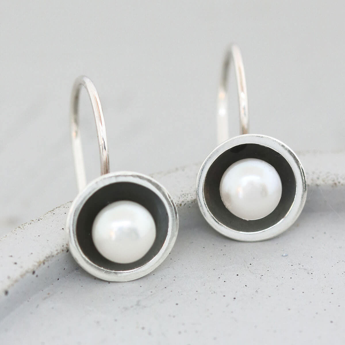 Modern black pearl hook earrings featuring domed oxidised sterling silver settings and genuine freshwater pearls.