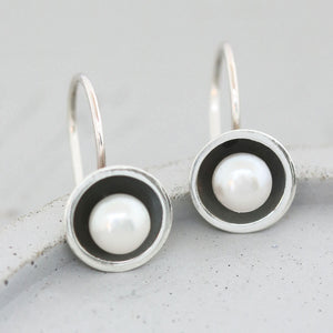 Modern black pearl hook earrings featuring domed oxidised sterling silver settings and genuine freshwater pearls.