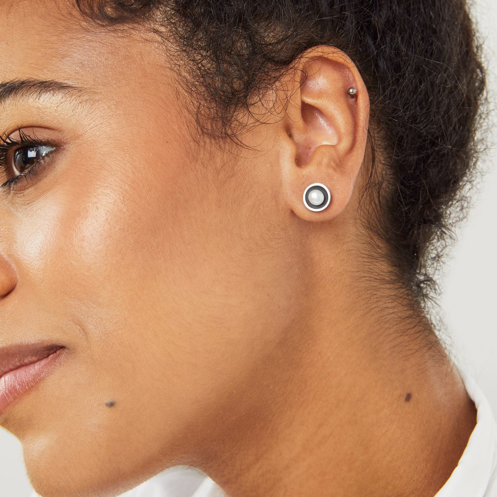 Black pearl stud earrings worn with hair up showing how the oxidised silver and pearl catch the light
