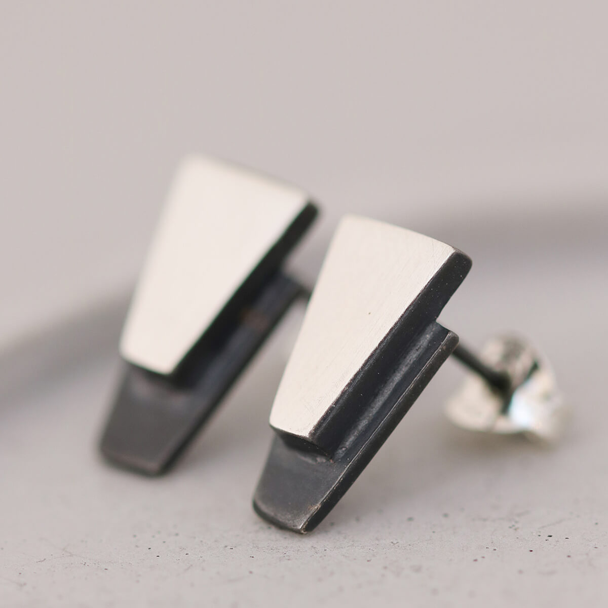 Geometric black stud earrings for women resting on grey dish, stylish sterling silver jewellery for milestone birthday gifts.