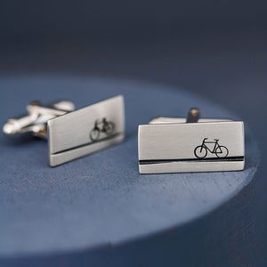 Silver cycling cufflinks on a deep blue background, ideal gift for bicycle lovers or best man gift for a cycling fan.