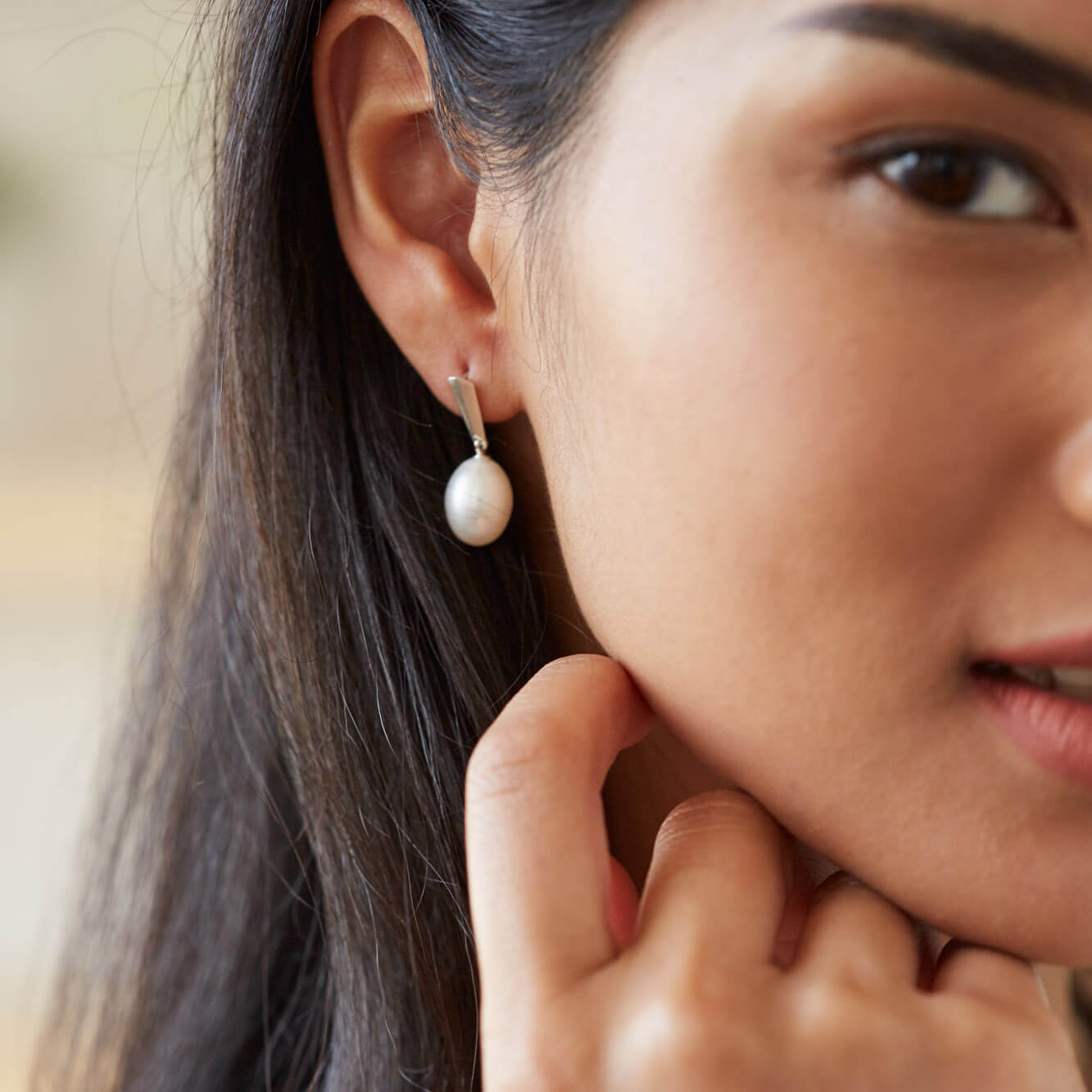 Model showcasing silver dangle pearl earrings as part of a bridal-inspired look, emphasising their refined sparkle.